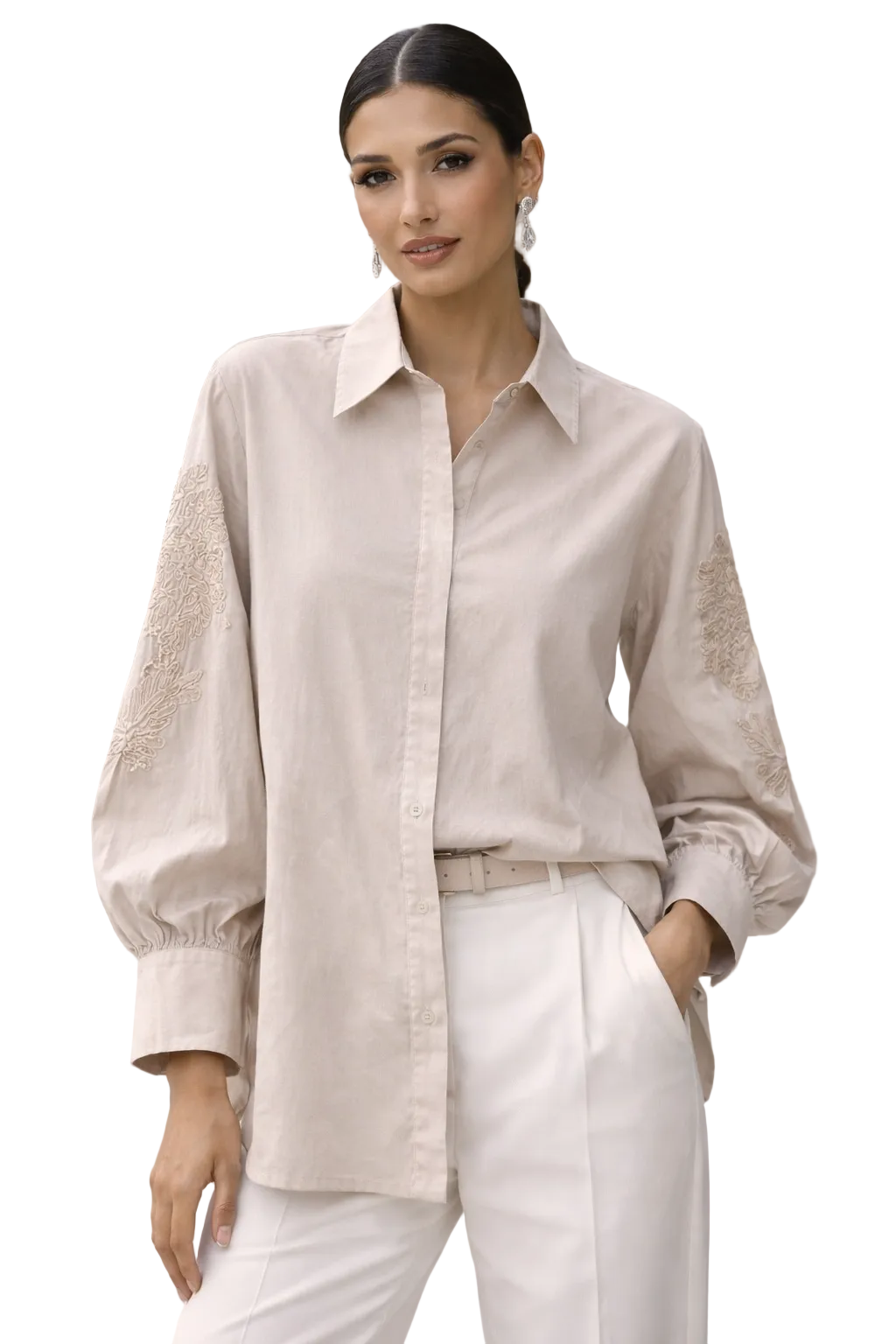Woman wearing a light beige button-up shirt with lace sleeves and white pants outdoors.