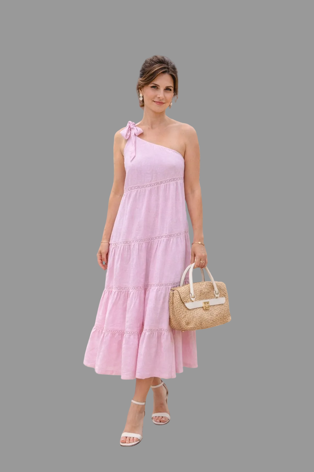 Woman in a pink dress standing on a beach with mountains and buildings in the background