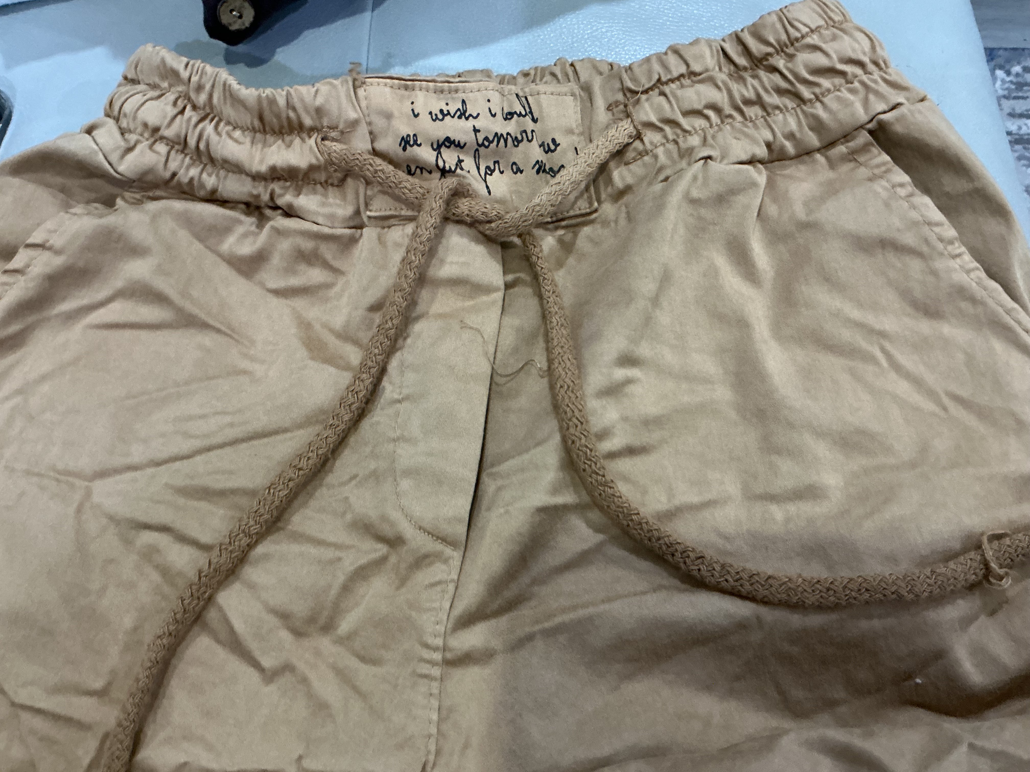 Beige shorts with a drawstring on a light blue surface