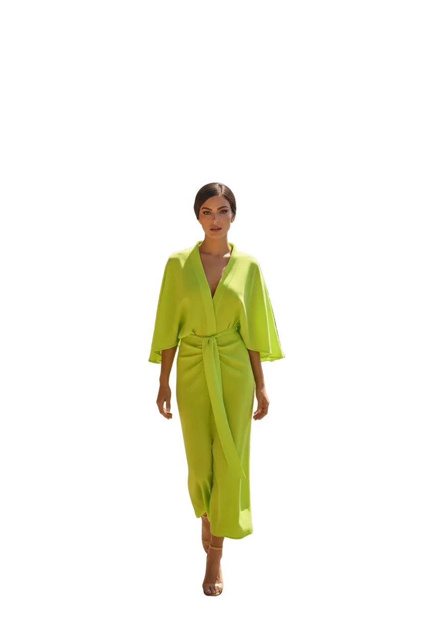 Woman in a bright green dress standing on a scenic road with ocean view