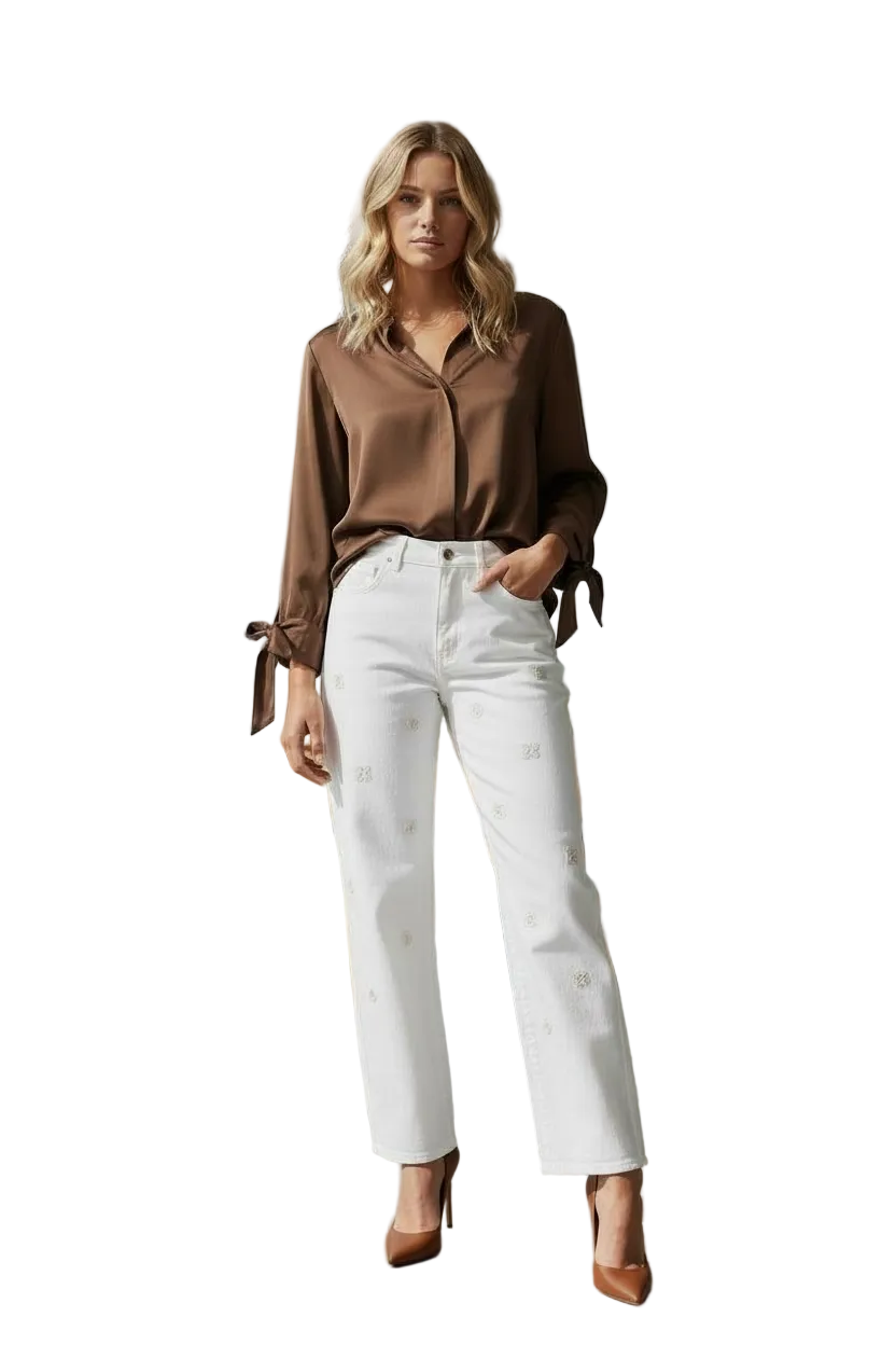 Woman in a brown blouse and white pants standing in a modern cafe.