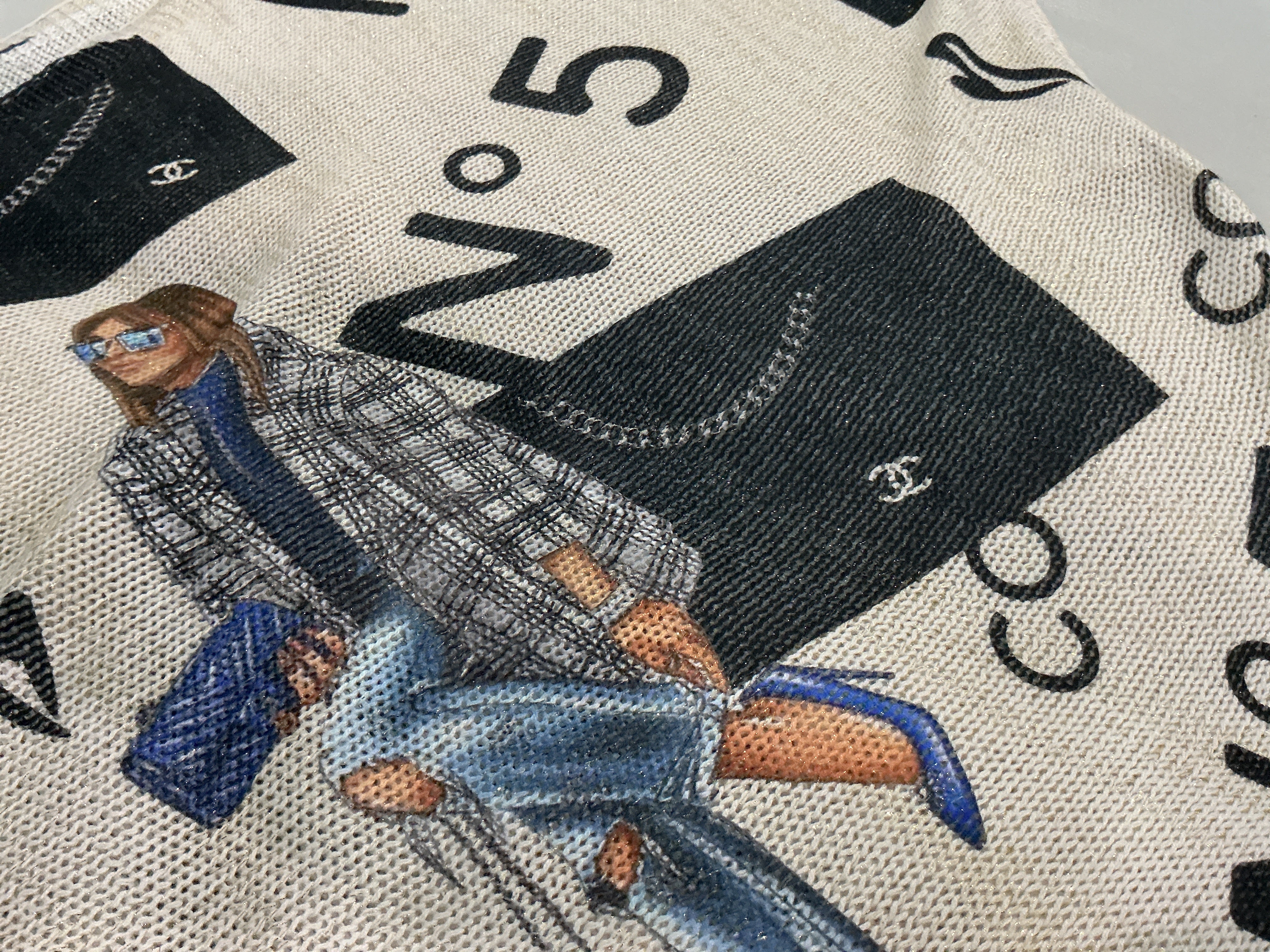 Close-up of a patterned fabric with a person, bags, and text design.