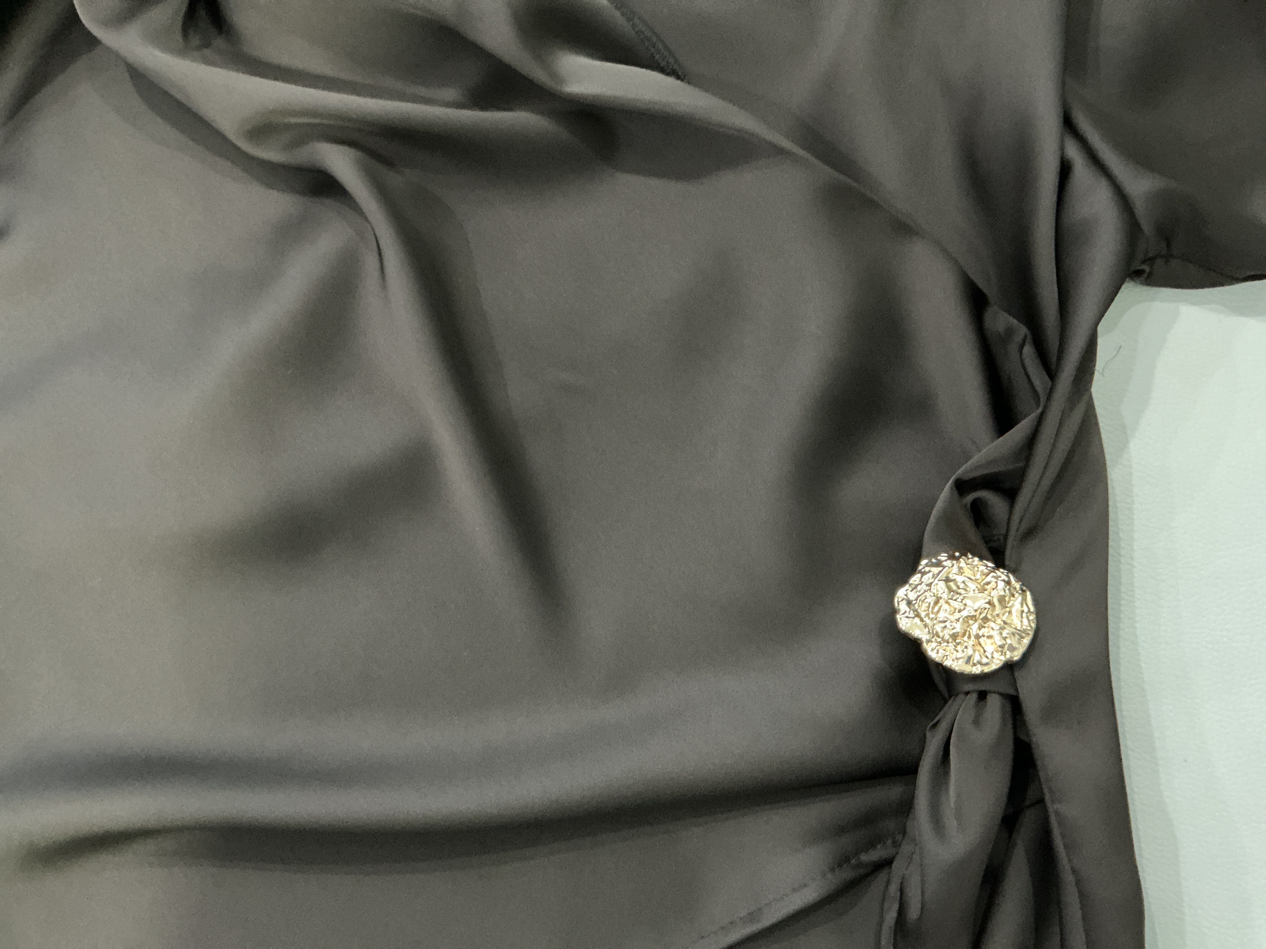 Dark gray fabric with a decorative brooch on a light gray background